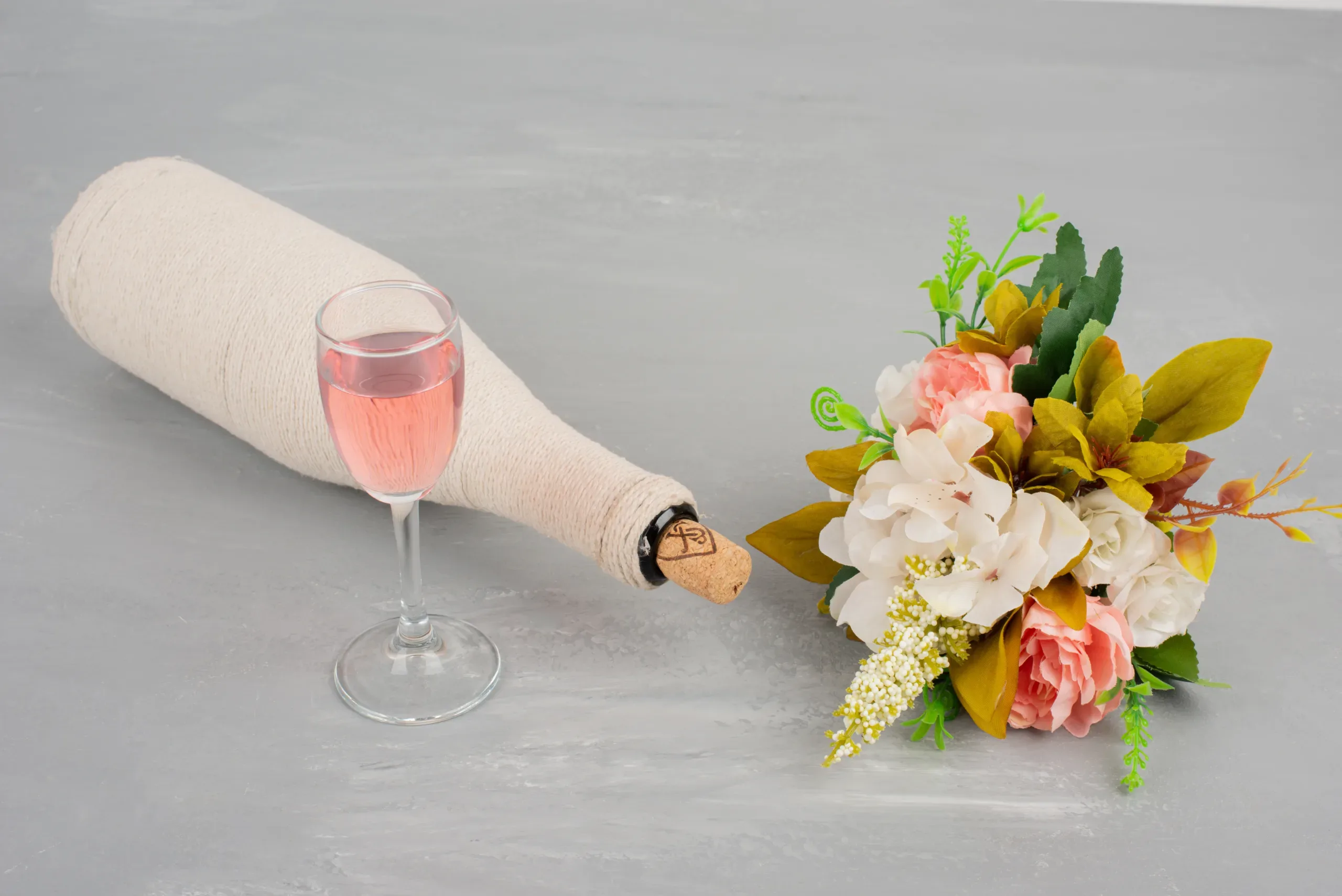 Bouquet of flowers and a glass of rose wine on grey surface